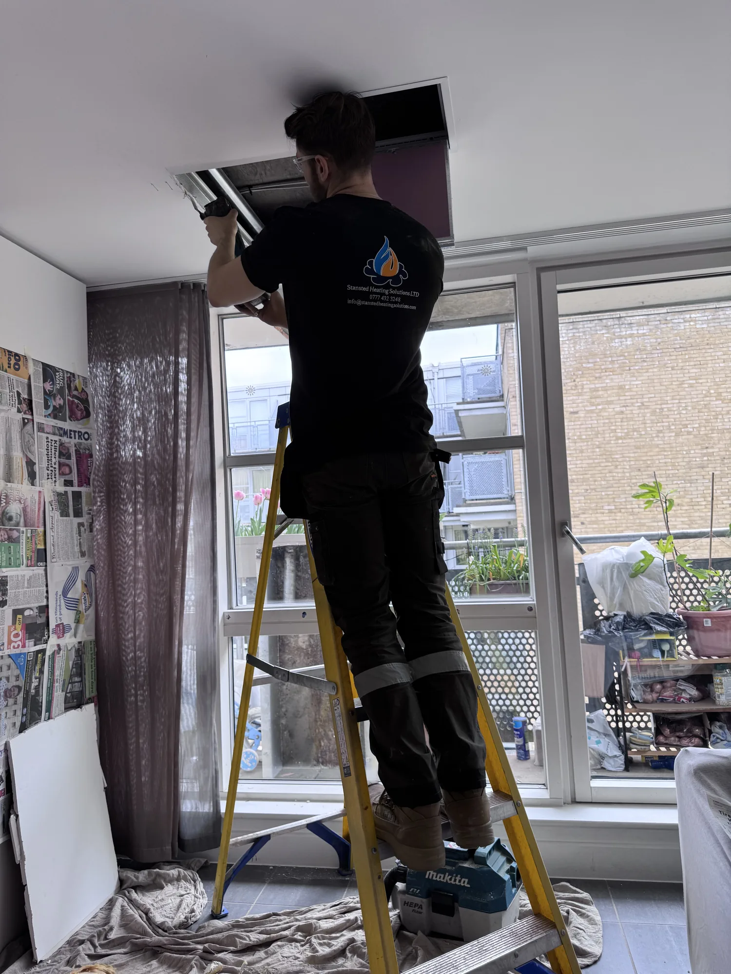 Thomas Baiss working at height on a flue during a heating job, Essex
