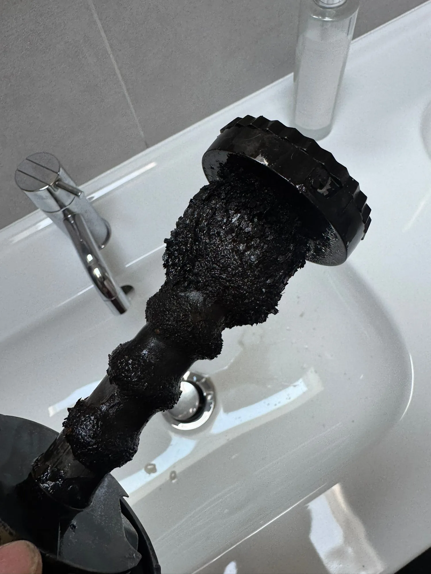 Power flush hose showing black sludge cleared from the heating system