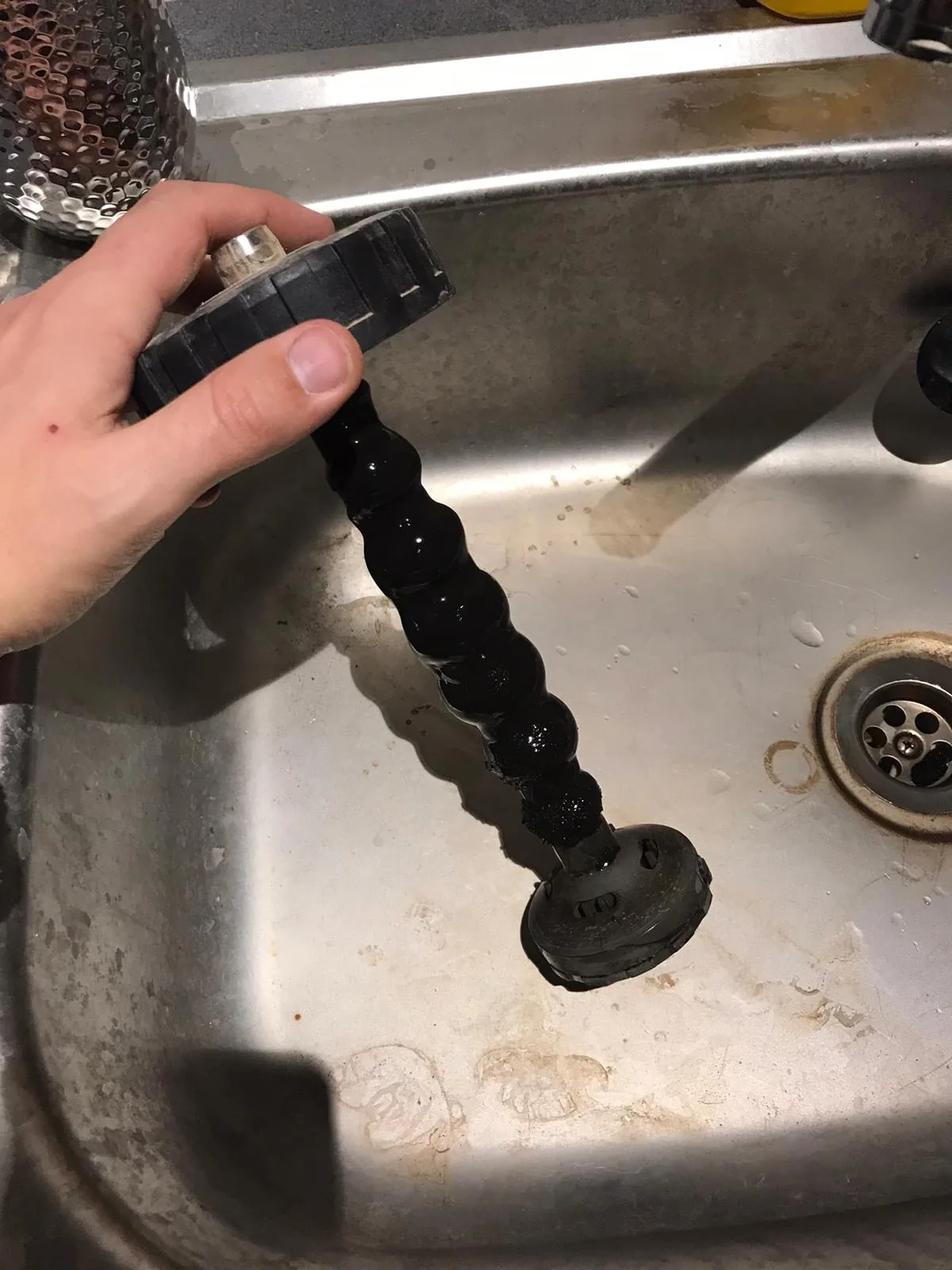 Black sludge being flushed from a central heating system into a sink
