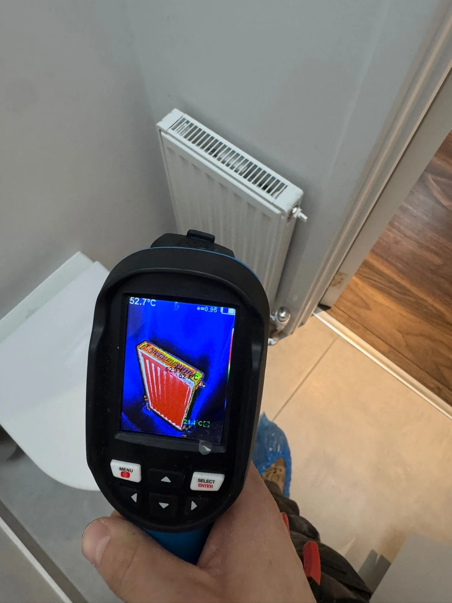 Thermal imaging camera checking a radiator for cold spots